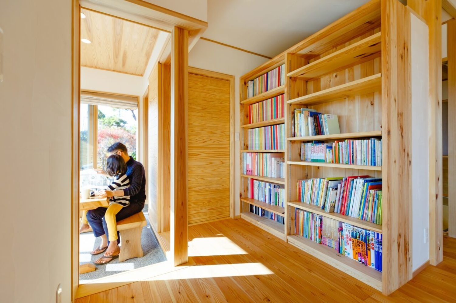 土間サロンとリビングの間に大きな本棚を設けました。子どもの絵本も仕事関係の本もここに集約でき、明るい土間サロンで読書ができます。すこし集中したいときには、本棚裏の書斎コーナーへ。