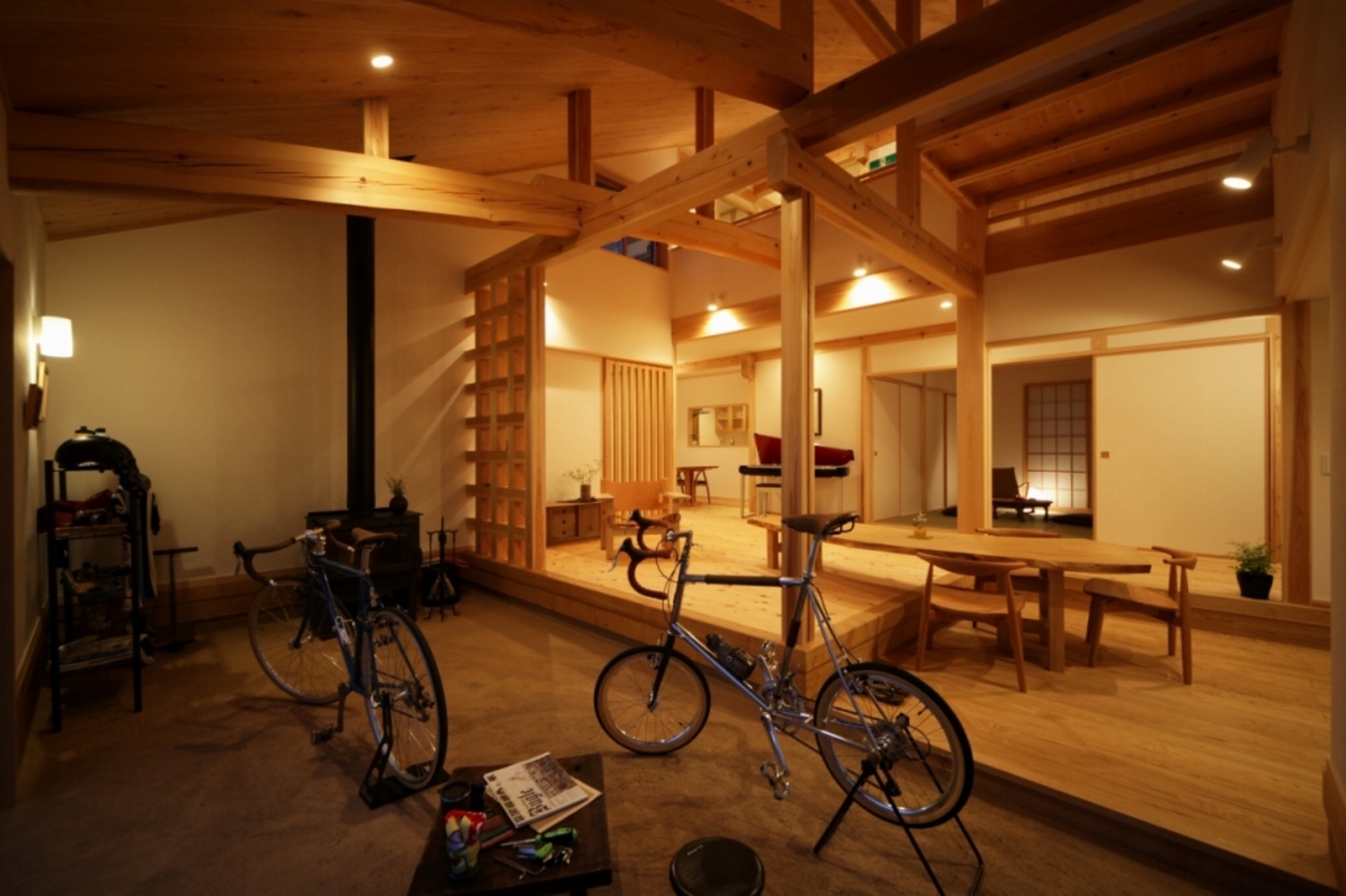 薪ストーブのある三和土の土間サロンと、カフェカウンターを設けた栗の床の居土間。中央のテーブルは曲がり栗の一枚板で、腰かけても座卓でも好きなスタイルでくつろげる。