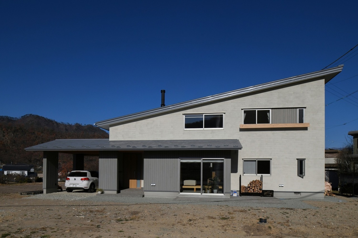 高さを抑えた片流れ屋根のファサード。ガレージ、玄関、土間まで大きく伸びた下屋が美しい水平ラインを強調する。