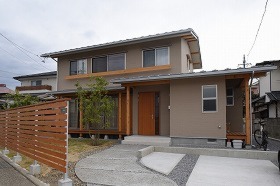 緩やかな三寸勾配の切妻屋根と、高さを抑えたスマートな外観に常緑樹のグリーンが映える。