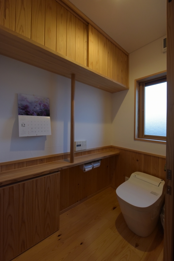 幅を広めに設計したトイレは、収納棚と手すりを木製で造作。日用品をきちんと収納できてすっきりと使える。