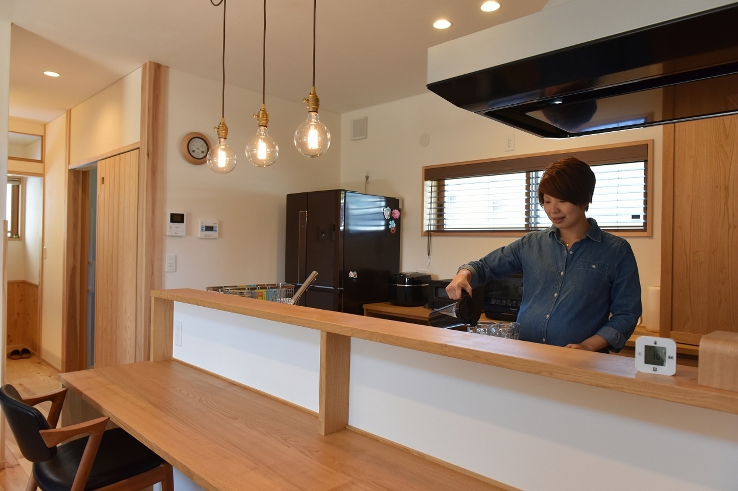 手元が隠れるカウンターキッチンですっきりと。三灯連なる真鍮製ペンダントライトにセンスが光る。