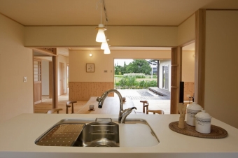 キッチンからの眺め。リビングダイニングと、フルオープンサッシの向こうに庭と安曇野の景観を一望できる。